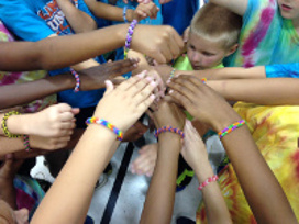 children in tie dye putting their hands in a circle